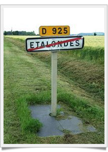 Une plaque anti herbe au pied d'un panneau de signalisation routière